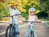 Deux fillettes au visage souriant essaient de garder l’équilibre à vélo