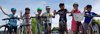 Un groupe d’élèves à vélos font signe en souriant
