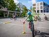 Un élève effectue un parcours à vélo sur la place de l’école. Il se concentre pour positionner correctement la balle.