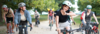 [Translate to Français:] Junge Lehrer:innen auf dem Velo. Eine Frau winkt freundlich in die Kamera.