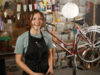 Une jeune fille qui a appris à réparer des vélos sourit dans un atelier de cycles